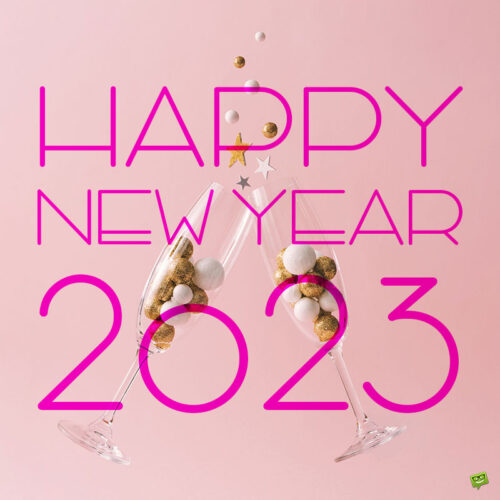 Happy New Year image for 2023 with champagne glasses filled with golden baubles. Happy New Year image with champagne glasses on pink background.