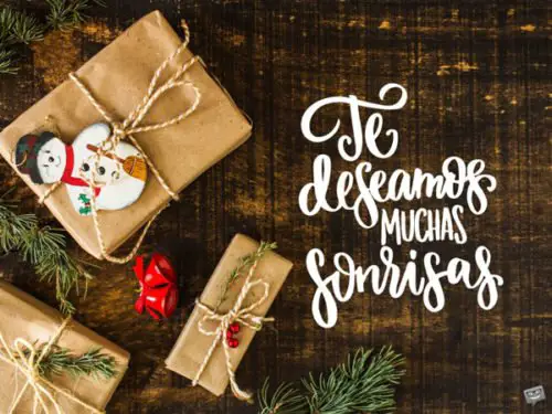 Una imagen con regalos y elementos decorativos navideños en un fondo que imita una mesa de madera para desear Feliz Navidad. Te deseamos muchas sonrisas.
